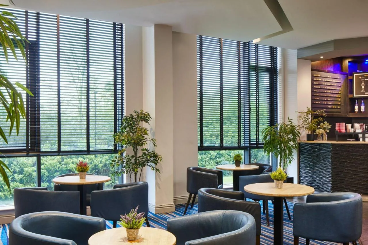 a restaurant with tables and chairs and large windows at Leonardo Hotel Newcastle in Newcastle upon Tyne